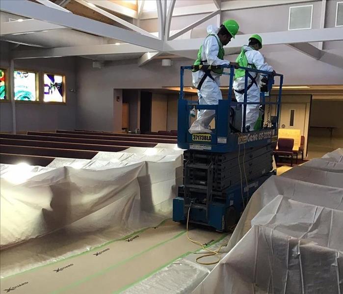 SERVPRO technicians by pews covered in plastic