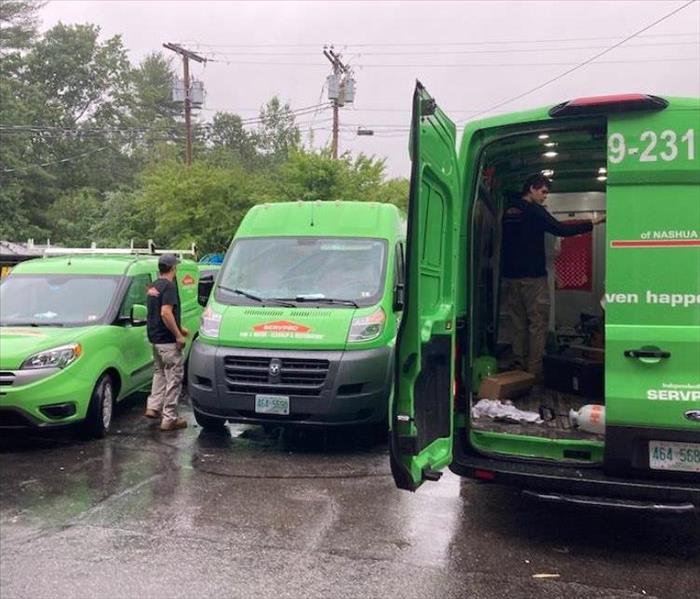 Three SERVPRO vehicles being loaded by technicians in a parking lot